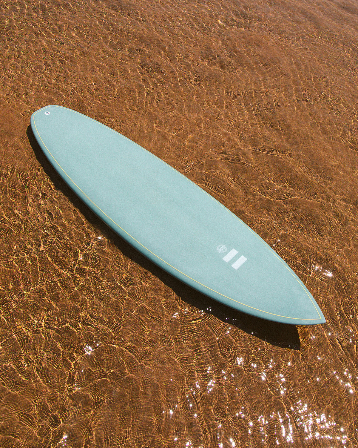 Indio Miggy surfboard showing its shape in shallow water